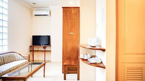 Una sala de estar con un sofá, una mesa de centro, un televisor, un armario de madera y una puerta.