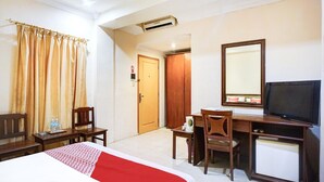 A hotel room with a bed, a desk with a chair, a television, and a wardrobe.