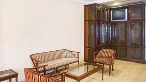 A living room with a sofa, armchairs, a glass coffee table, and a television on a cabinet.
