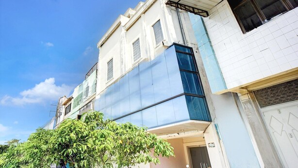 A multi-story building with a blue facade, a white door, and a tree in the foreground.