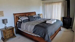Un dormitorio con una cama de madera, una mesita de noche, una lámpara y una chimenea.