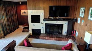 Una sala de estar con chimenea, televisor y sofá.