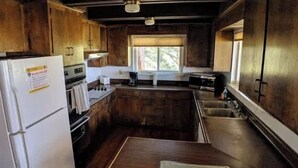 Una cocina compacta con armarios de madera, un refrigerador, una estufa y un ventanal que proporciona luz natural.