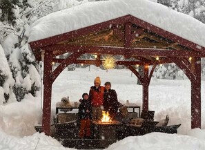 A snow-covered outdoor area with a wooden structure, possibly a gazebo, and a fire pit. - New! Walking distance to the lake and beach! (Kings Beach)