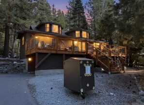 A cabin with a wooden deck, a staircase, and a large metal box in front. - New! Walking distance to the lake and beach! (Kings Beach)