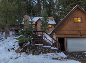 Eine Hütte mit einer Steintreppe, einer Garage und einer Holzterrasse.