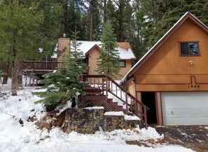 A wooden cabin with a stone staircase, a garage, and a forested backdrop. - Cabin close to hiking trails and ski resorts (South Lake Tahoe)