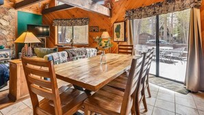 Un interno in legno con un tavolo da pranzo, sedie, un divano, una televisione e una finestra vista esterna.