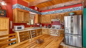 Una cucina con mobili in legno, un frigorifero in acciaio inossidabile e un tavolo da pranzo in legno.