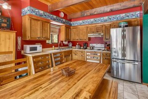 Una cocina con armarios de madera, un refrigerador de acero inoxidable y una mesa de comedor de madera.
