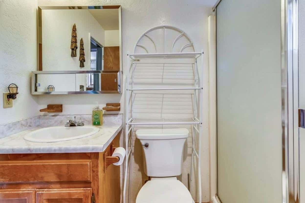 Un baño con lavamanos doble, inodoro, espejo y toallero.