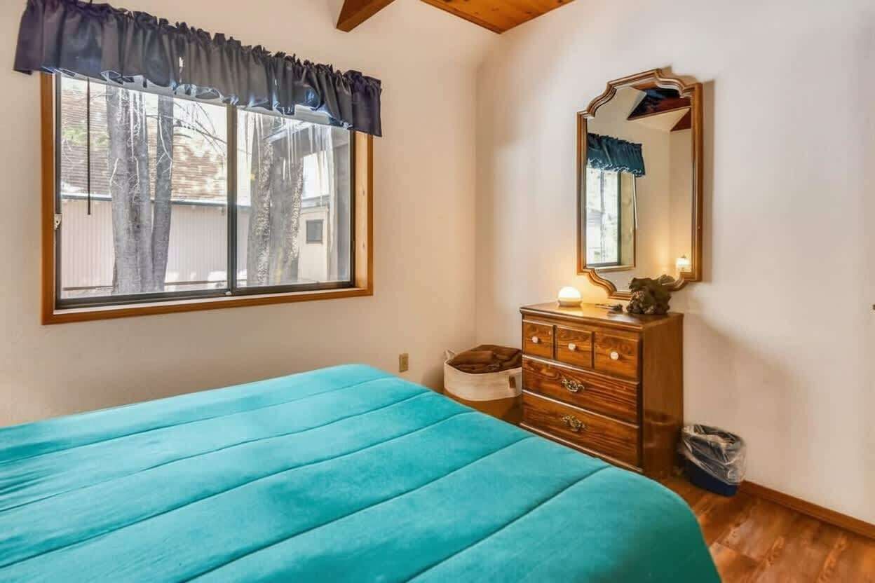 Ein Schlafzimmer mit Bett, Schminktisch, Spiegel und einem Fenster mit Vorhängen.