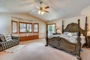 Ein Schlafzimmer mit einem Himmelbett, einem Deckenventilator und einem Fenster mit Jalousien.