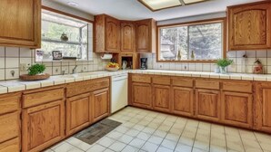Una cucina con mobili in legno, lavastoviglie e una finestra vista alberi.
