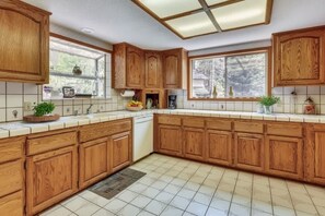 A kitchen with wooden cabinets, a dishwasher, and a window with a view of trees. - Minutes to Heavenly, Private Covered Hot Tub (South Lake Tahoe)