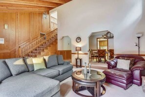 A living room with a gray sectional sofa, a round coffee table, and a leather armchair. A staircase is visible in the background. - Minutes to Heavenly, Private Covered Hot Tub (South Lake Tahoe)