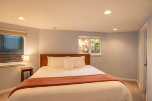 Ein Schlafzimmer mit Bett, Nachttisch, Fenster und Tür.