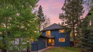 A two-story house with a dark blue exterior, a front porch, and a visible garage. - Private Beach, Lakefront Home, Close to Everything (South Lake Tahoe)