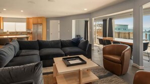 A modern living room with a sectional sofa, a coffee table, and a dining area with a view. - Private Beach, Lakefront Home, Close to Everything (South Lake Tahoe)
