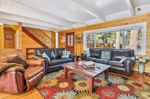 Ein gemütliches Wohnzimmer mit Ledersofas, einem Couchtisch und einem farbenfrohen Teppich.