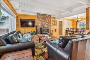 Ein Wohnzimmer mit Kamin, Ledersofas, einem Fernseher und einem Essbereich mit Stühlen.