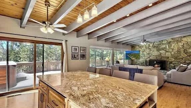 Un'ampia cucina con un'isola grande, travi in legno al soffitto e una parete decorativa in pietra.