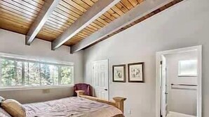 Una camera da letto con un letto, una finestra, una porta e due quadri appesi al muro.