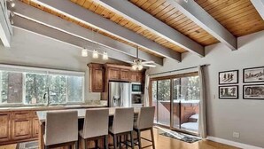 Una cucina moderna con mobili in legno, una grande isola con sgabelli da bar e una ventola a soffitto.