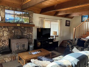 Una sala de estar acogedora con chimenea de piedra, televisor y sofá.
