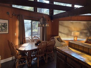 Un comedor con una mesa y sillas de madera, un banco y una encimera de cocina.