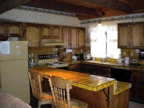 A kitchen with wooden cabinets, a central island, a refrigerator, and a stove.