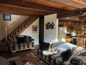 Ein Wohnzimmer mit einer Couch, einem Couchtisch und einer Treppe, die zu einer anderen Ebene führt.