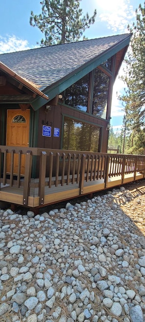 A lodge with a wooden deck, a large window, and a door with a mountain design.