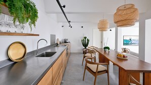 Cocina moderna con encimera de madera, pileta de acero inoxidable y lámparas colgantes de mimbre.