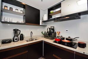 A modern kitchen with a built-in dishwasher, a coffee maker, a microwave, and a stove. - Studio Shopping OKA Floripa - SOK239 (Florianópolis)