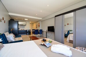 Una habitación de hotel moderna con cama, sofá, zona de comedor y cocina.