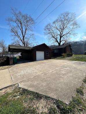 A two-story building with a garage, a covered porch, and a grassy yard.