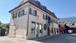 Un edificio de dos pisos con un letrero que dice 'NICOLET VINS' y un balcón.