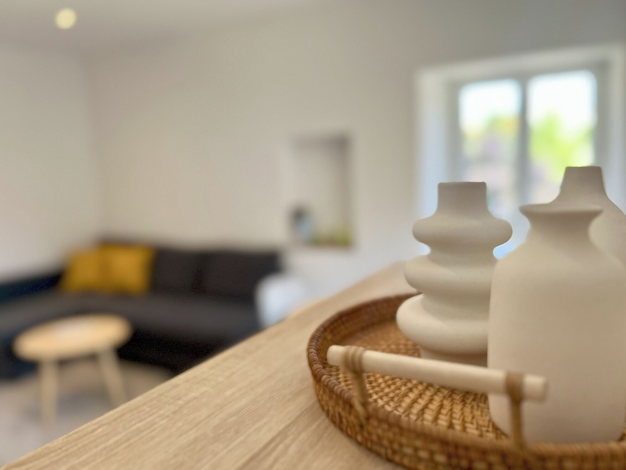 A modern living room with a sofa, a small table, and decorative vases on a tray.