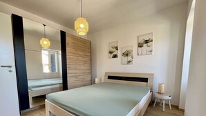 Un dormitorio con cama, mesita de noche, espejo y cuadros en la pared.