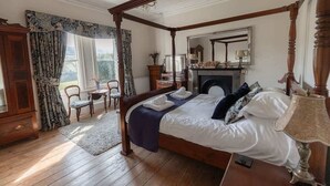 A four-poster bed with a canopy, a fireplace, a mirror, and a chandelier.