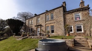 A stone building with a hot tub, steps, and a lawn.