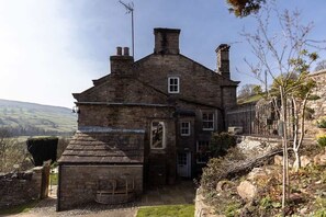 Ein Steinhaus mit Schornstein, kleinem Fenster und einer Tür.