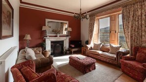 A living room with a fireplace, sofas, a television, and a large window with curtains.