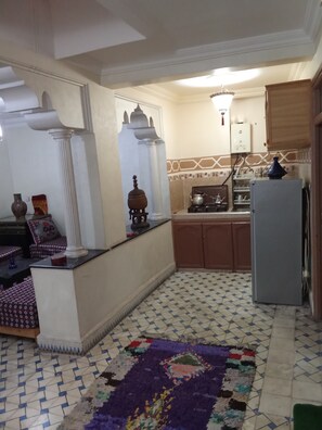 Una cocina con piso de baldosas, un refrigerador y un lavamanos.