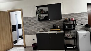 Una cocina compacta con microondas integrado, cafetera y un refrigerador pequeño.