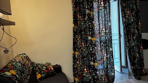 Una habitación con cama, escritorio y ventana con cortinas.