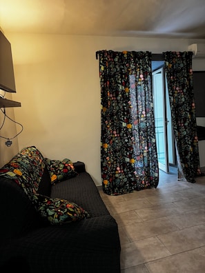 Ein Zimmer mit einem Bett, einem Schreibtisch und einem fenster mit Vorhängen.