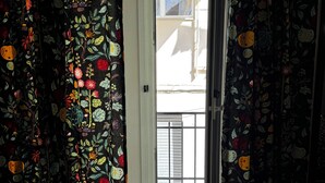 Una habitación con cama, una puerta que da al exterior y cortinas con estampado de frutas.