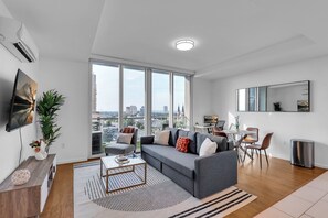 A modern living room with a grey sofa, a coffee table, and a dining area with a small table and chairs.